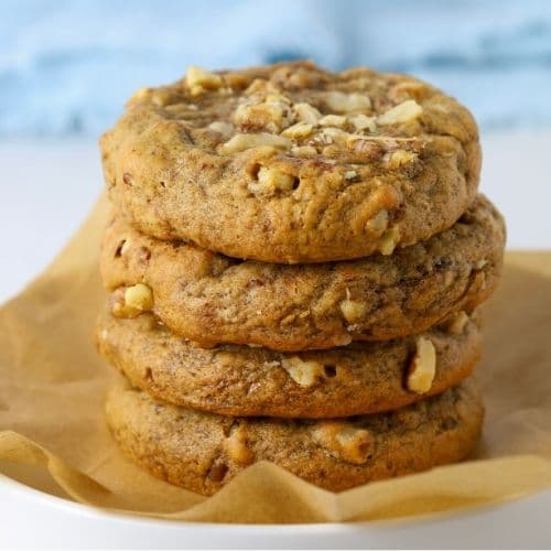Sourdough date and walnut cookies stacked on a parchment paper lined plate.