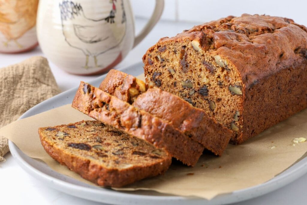 Sourdough date and walnut loaf cake sliced on a plate for serving.