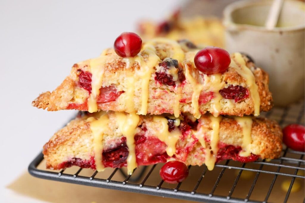 Two sourdough orange and cranberry scones stacked on a wire cooling rack.