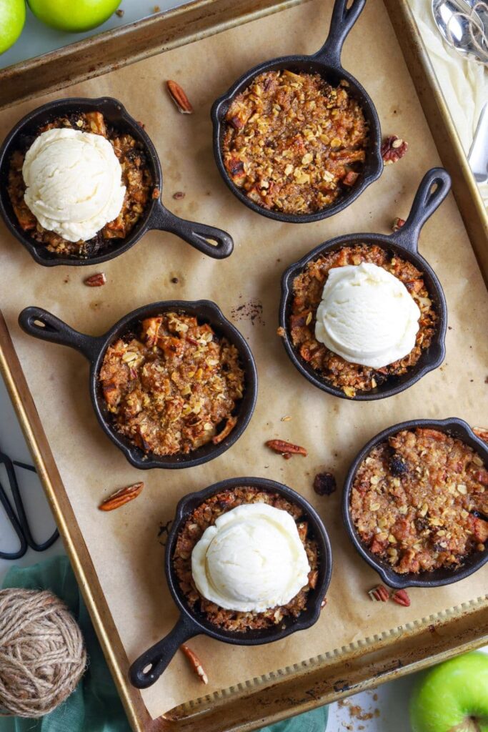 6 mini cast iron skillets filled with a cobbler topped with sourdough streusel topping and ice cream.
