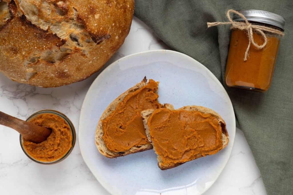 A horizontal image of two slices of sourdough bread spread with pumpkin butter.