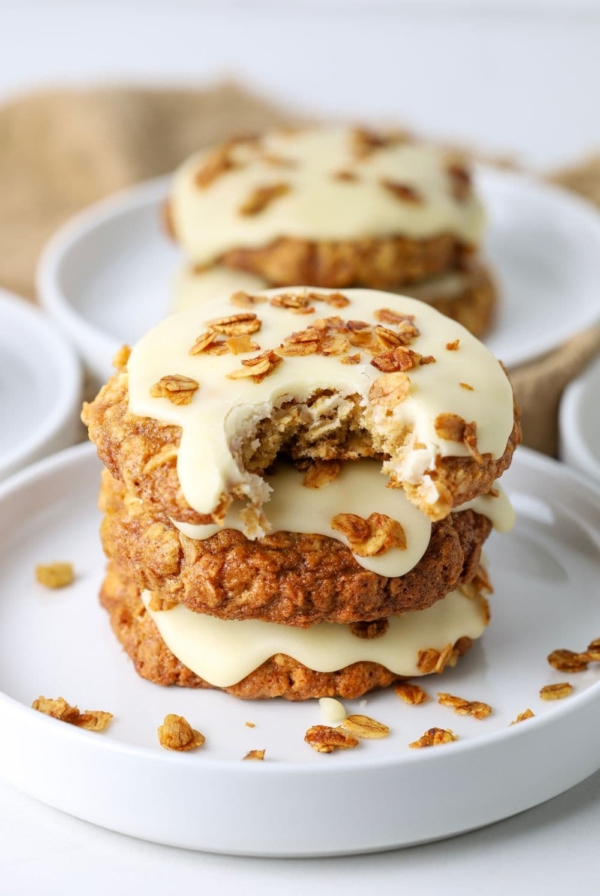 Three sourdough honey oat cookies stacked on a plate with a bite taken out of the top cookie.
