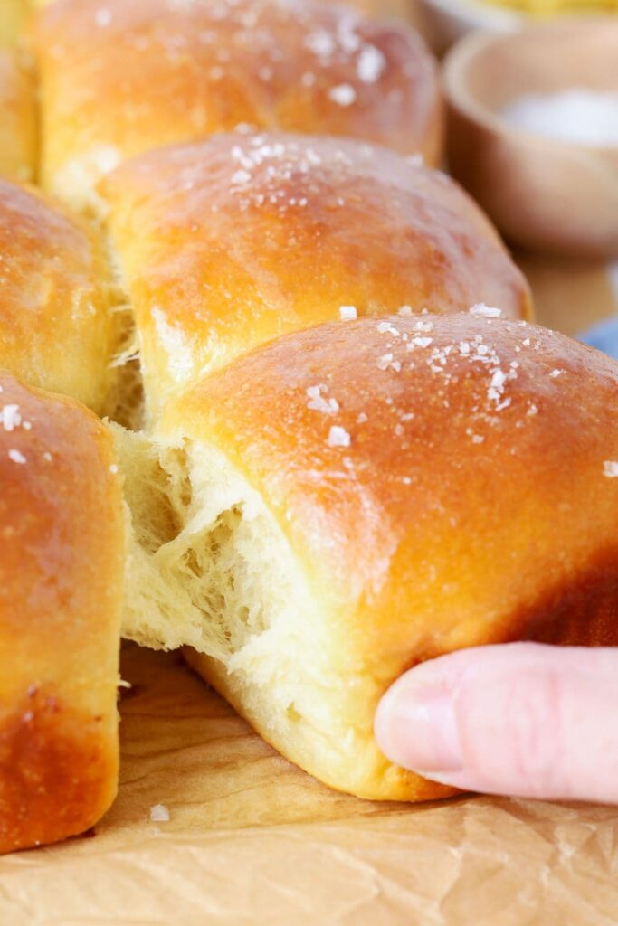 A batch of sourdough honey butter dinner rolls being pulled apart.