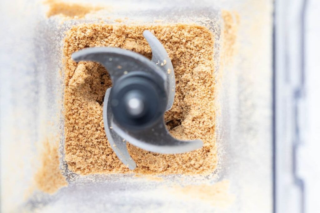 View of the inside of the blender to show blitzing roasted hazelnuts into a ground power to make homemade Nutella.