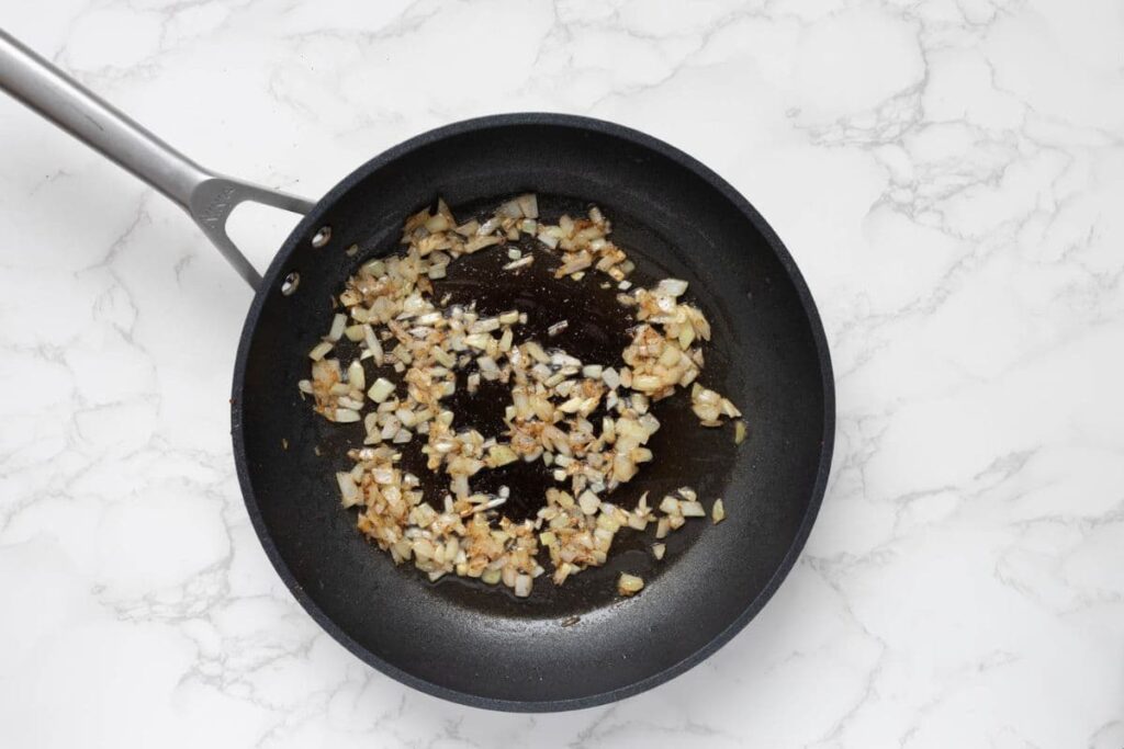 Saut&eacute;ing onions in a pan to make bacon jam.
