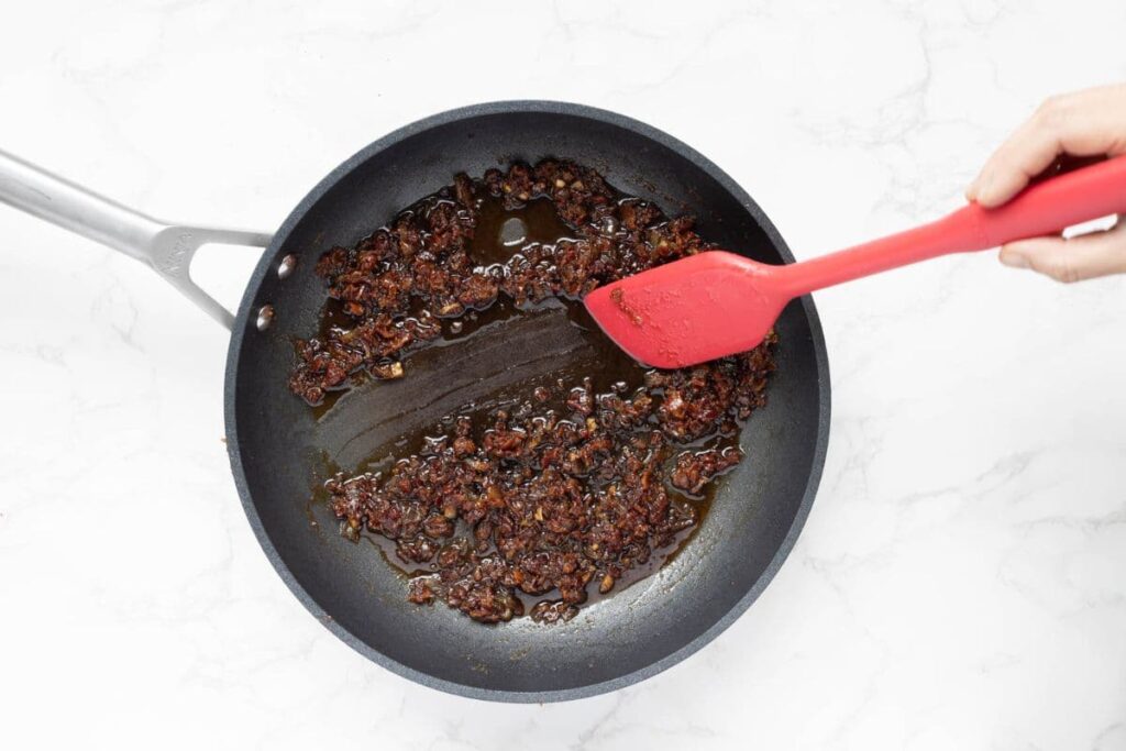Showing the texture of cooked bacon jam in a pan.