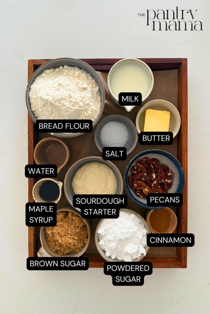 Labeled ingredients in wooden box to make a maple pecan sourdough twist loaf.