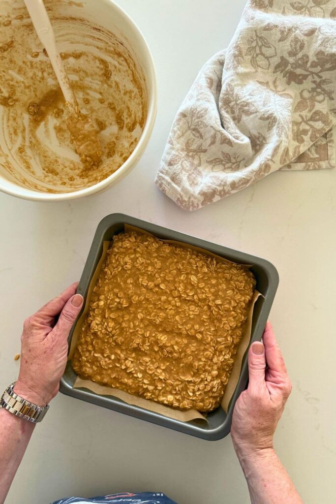 Batter emptied from mixing bowl into baking pan to make sourdough baked oatmeal.