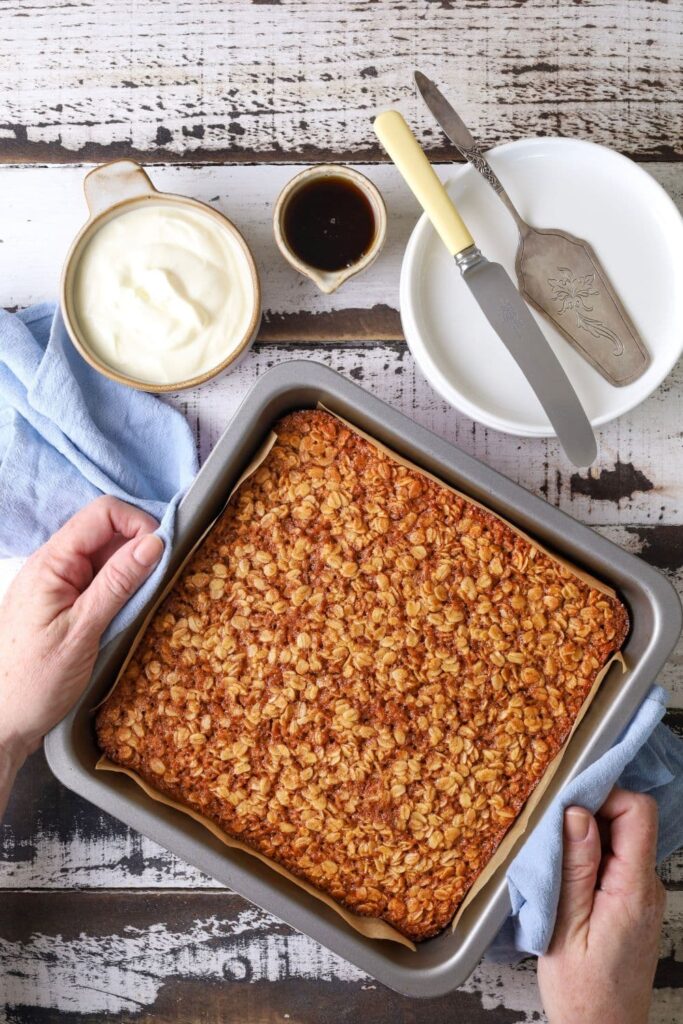 Fresh baked sourdough baked oatmeal in pan on wooden table.