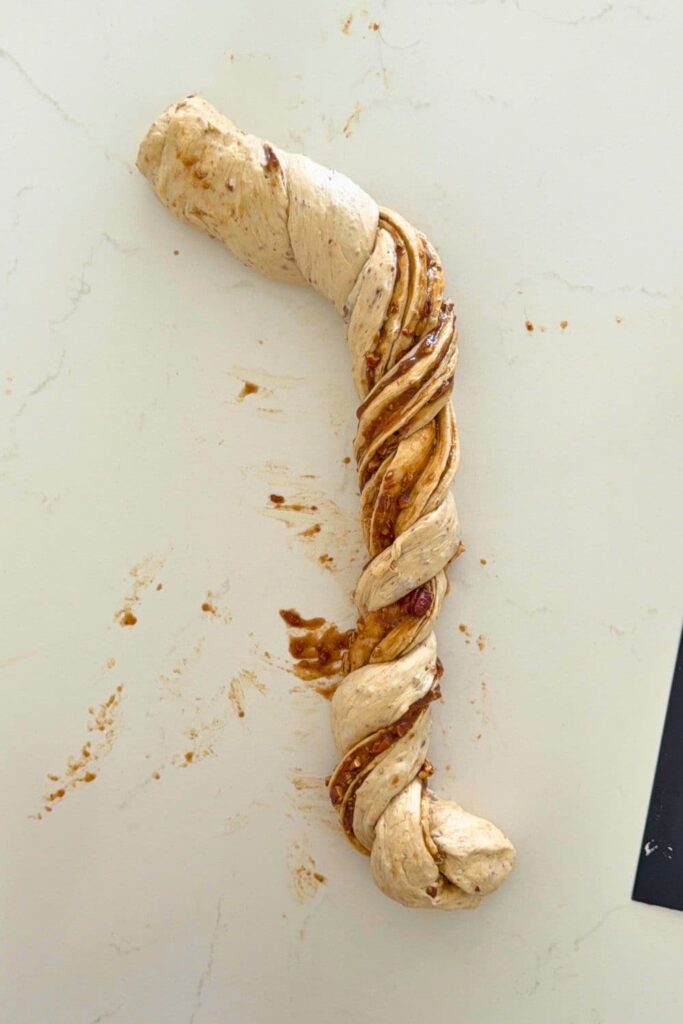 Shaping the rope dough into an S to form the twist for sourdough maple pecan twist loaf.
