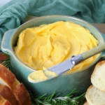Close up of cheddar butter in a serving bowl with a butter knife for spreading onto bread.