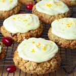 Orange cranberry sourdough oatmeal cookies with orange glaze and sprinkled with orange zest on a cooling rack.