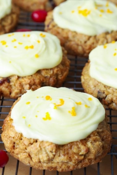 Orange cranberry sourdough oatmeal cookies with orange glaze and sprinkled with orange zest on a cooling rack.