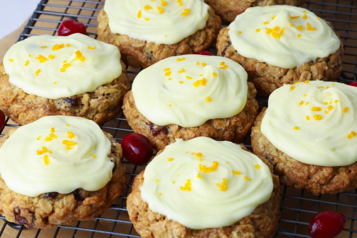Orange cranberry sourdough oatmeal cookies on a cooling rack topped with an orange butter glaze and orange zest.