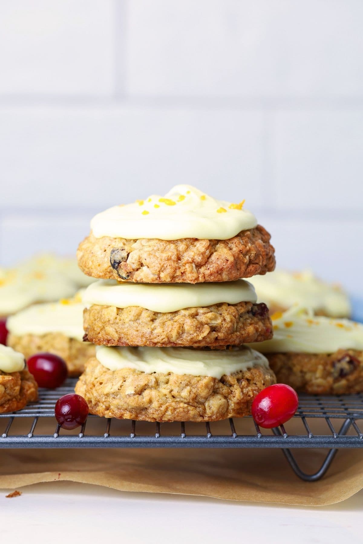 Three orange cranberry sourdough oatmeal cookies stacked on a cooling rack to show cookie texture.