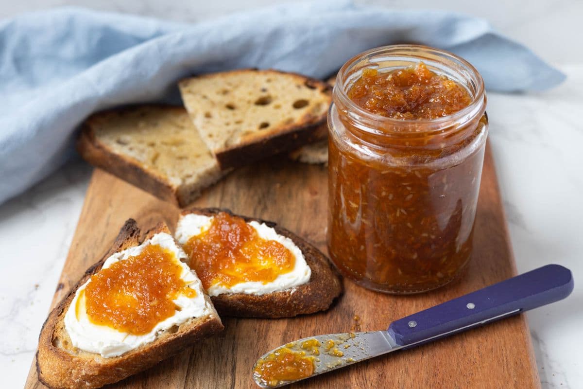 A jar of carrot cake jam next to sourdough toast spread with the jam for serving.