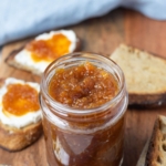 A jar of carrot cake jam on a serving platter and spread onto sourdough toast.