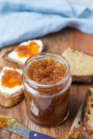 A jar of carrot cake jam on a serving platter and spread onto sourdough toast.