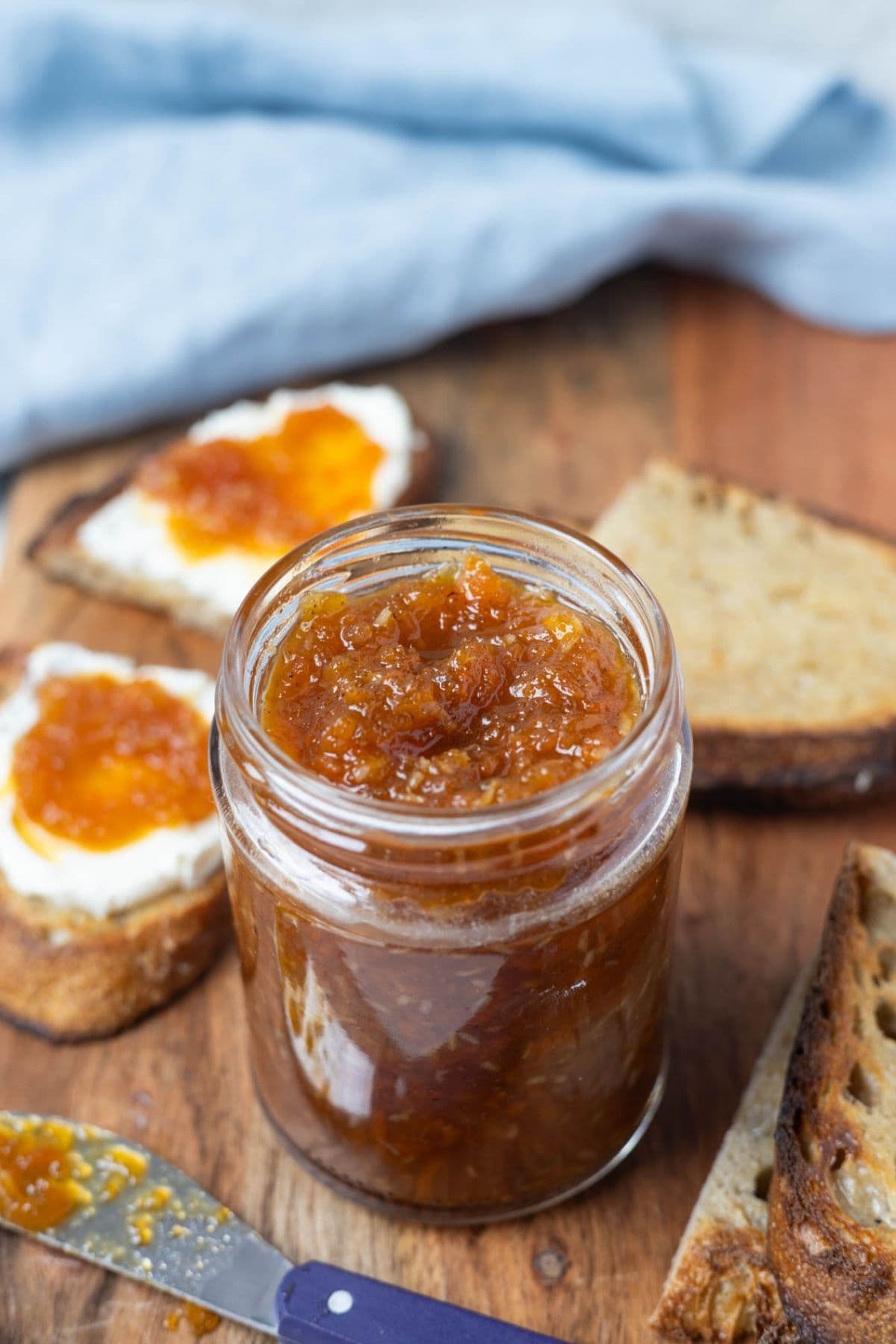 A jar of carrot cake jam on a serving platter and spread onto sourdough toast.