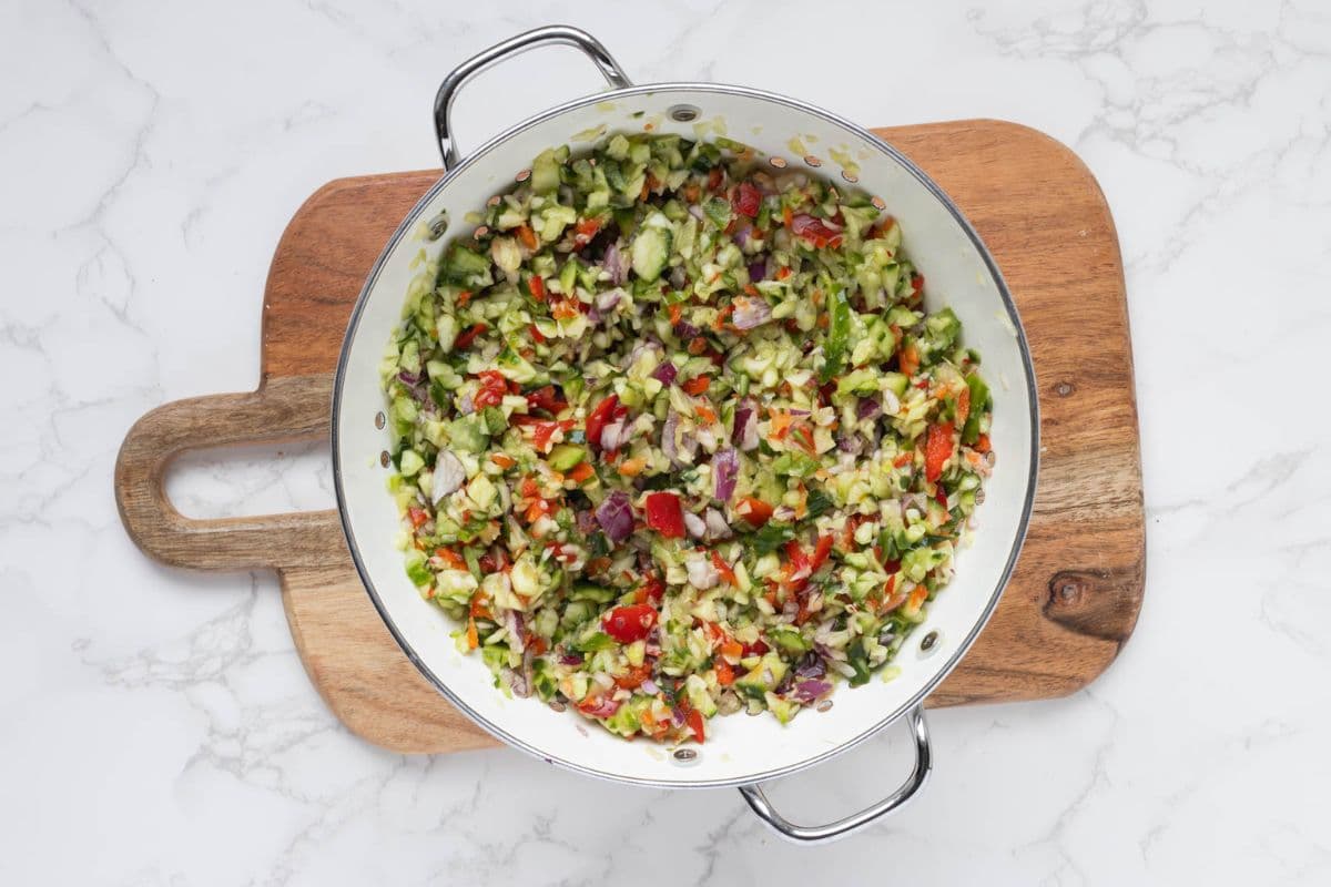 Draining excess water out of chopped vegetables in a colander.