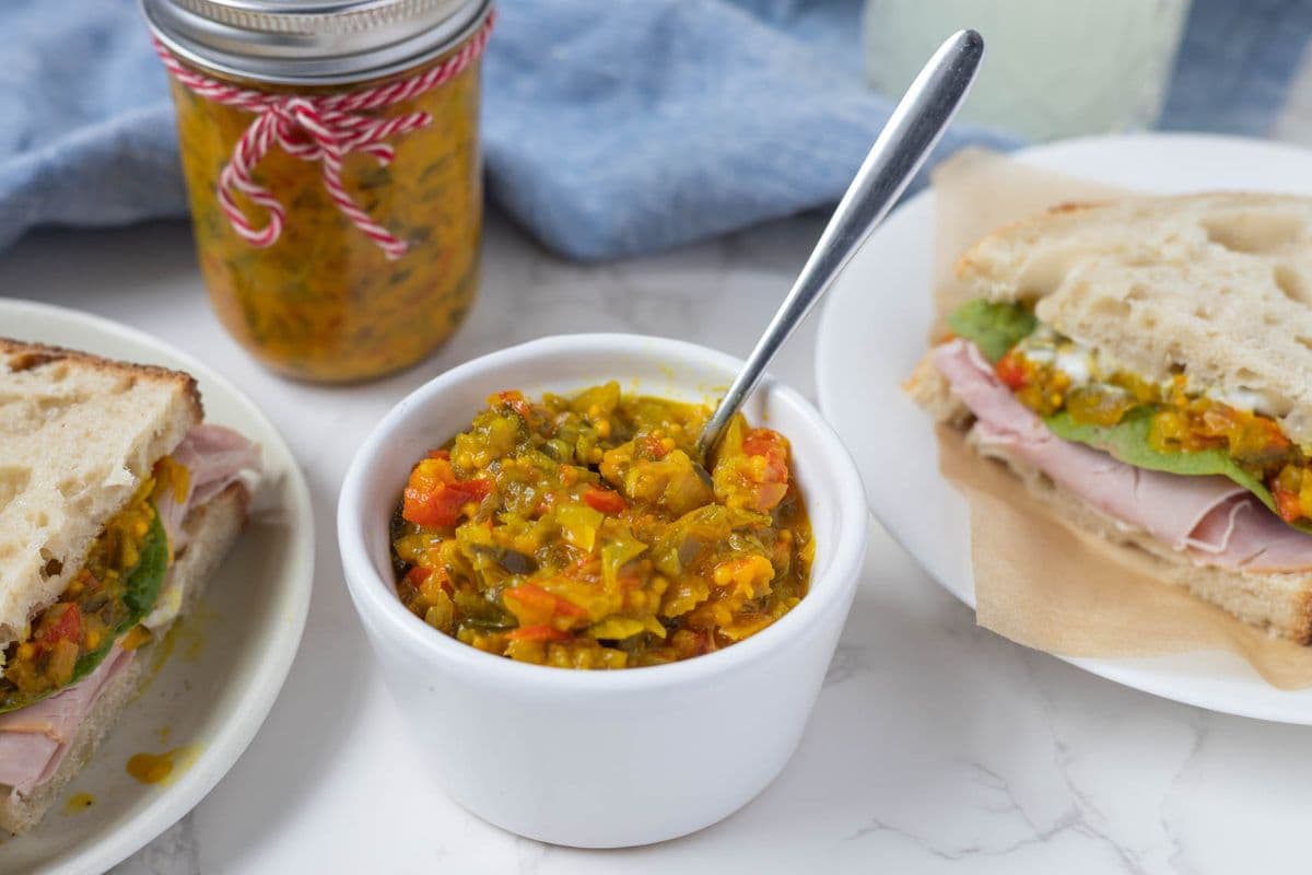 Mustard relish in a bowl with a spoon after being added to a sandwich.