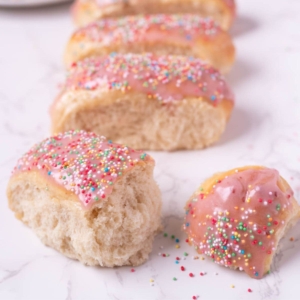 Sourdough discard iced buns on the counter with one split open to show texture.