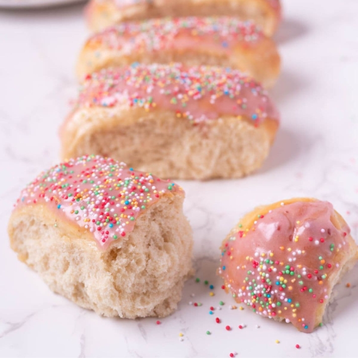Sourdough discard iced buns on the counter with one split open to show texture.