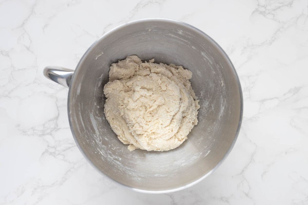 A shaggy dough for sourdough discard iced buns in a mixing bowl.