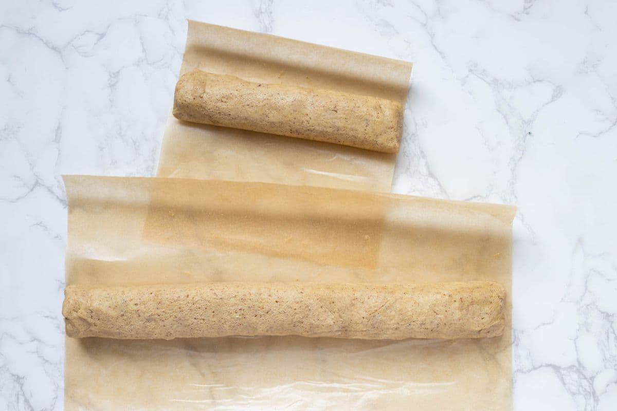 Rolling the dough for sourdough discard pecan sandies into a log with parchment paper.