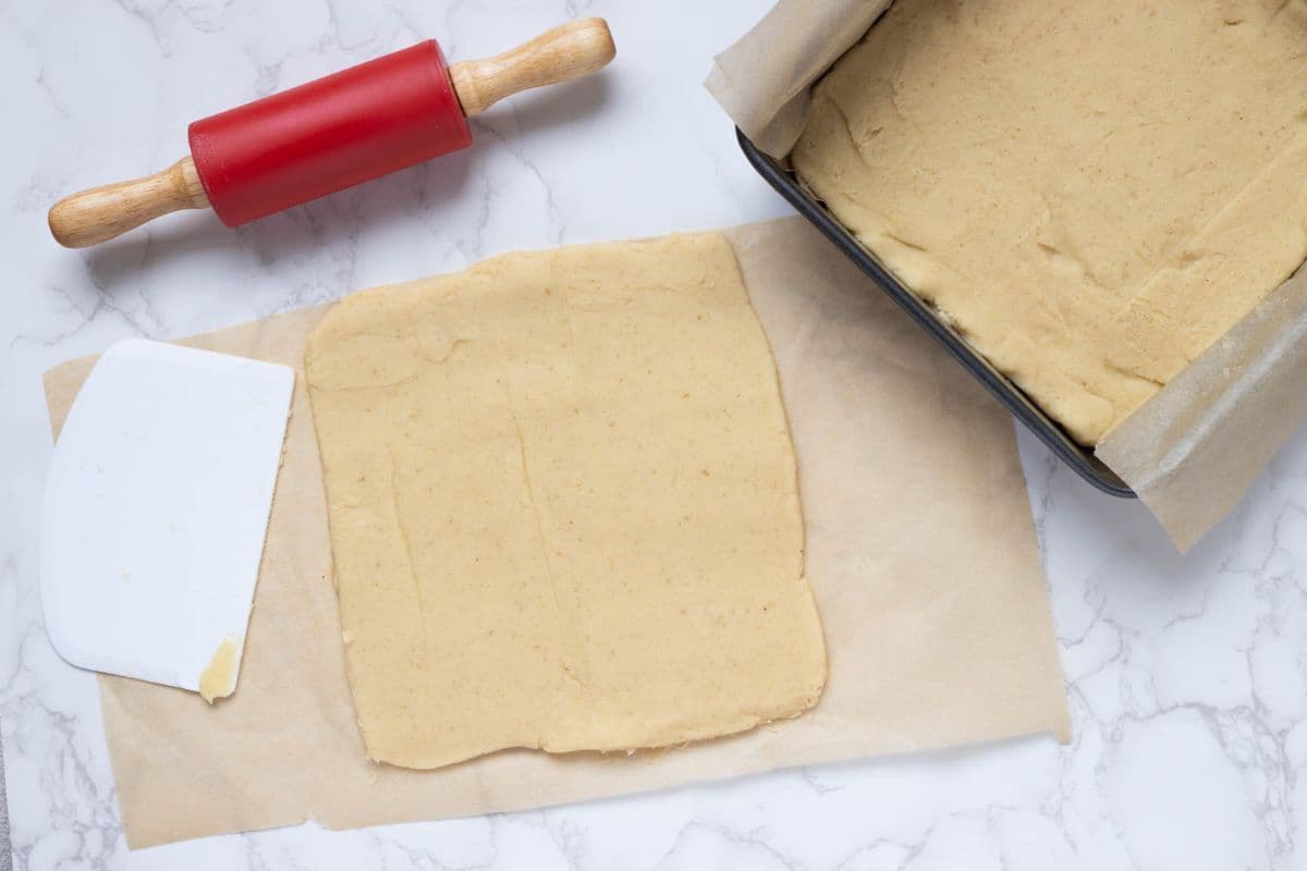 Smoothing out shortbread dough and adding it to the pan to make sourdough twix cookies.