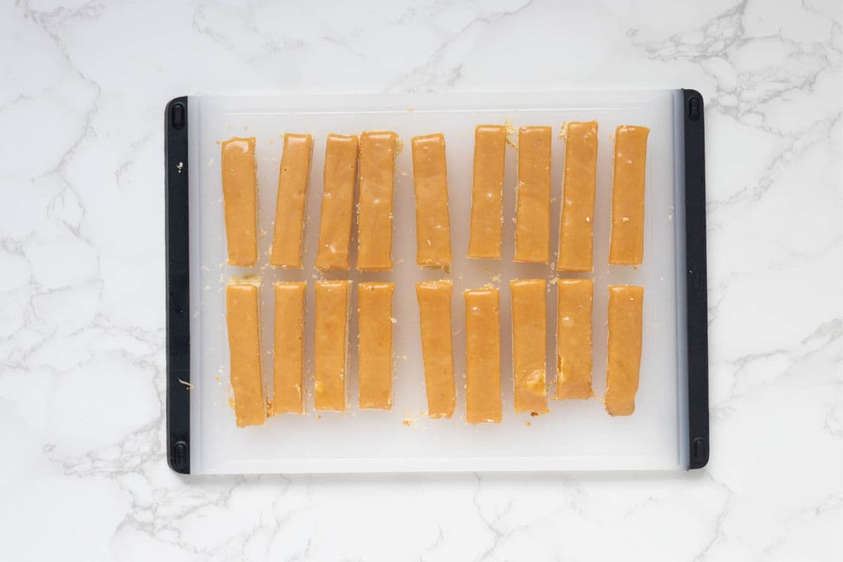 Caramel covered shortbread bars on a cutting board to make sourdough twix cookies.