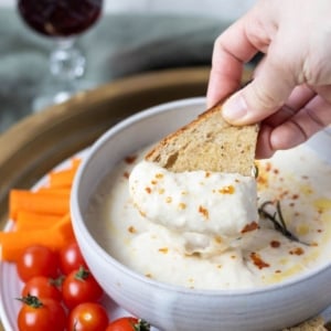 Dipping a piece of sourdough toast into white bean dip.