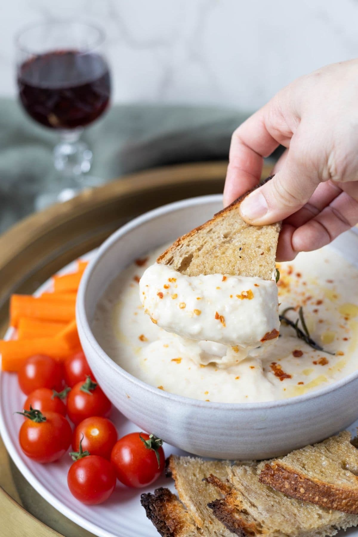 Dipping a piece of sourdough toast into white bean dip.