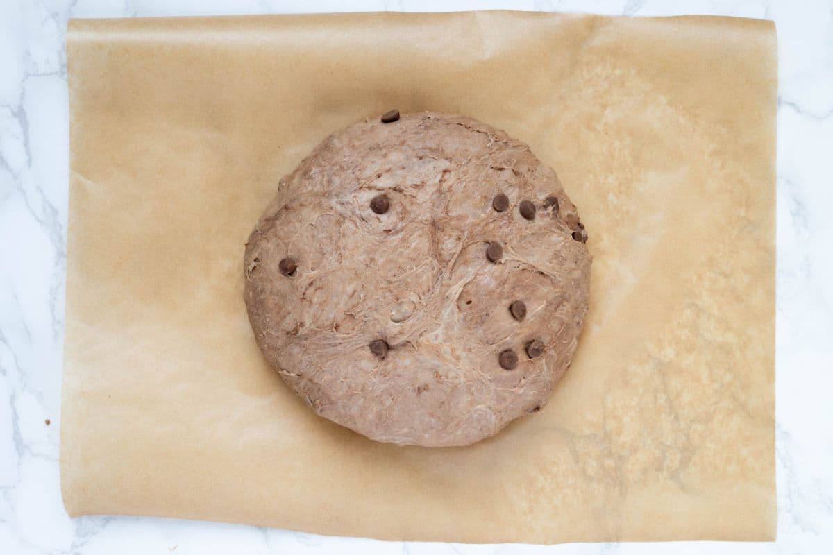 Chocolate sourdough discard bread dough on a piece of parchment paper ready to bake.
