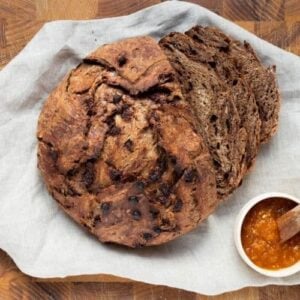 A loaf of chocolate sourdough discard bread on a cutting board, sliced for serving with jam.