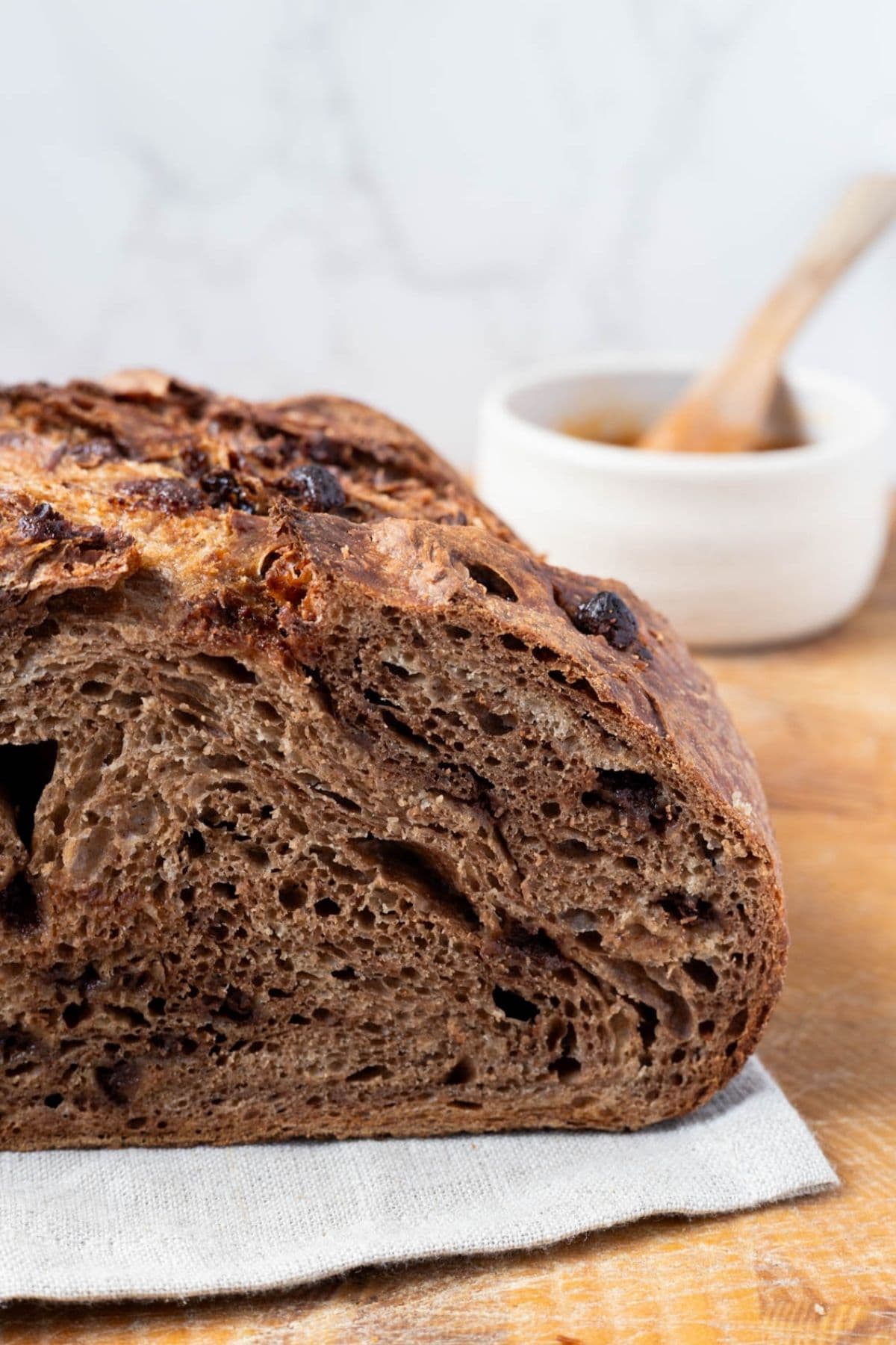 Close up of a loaf of chocolate sourdough discard bread being sliced on a cutting board.