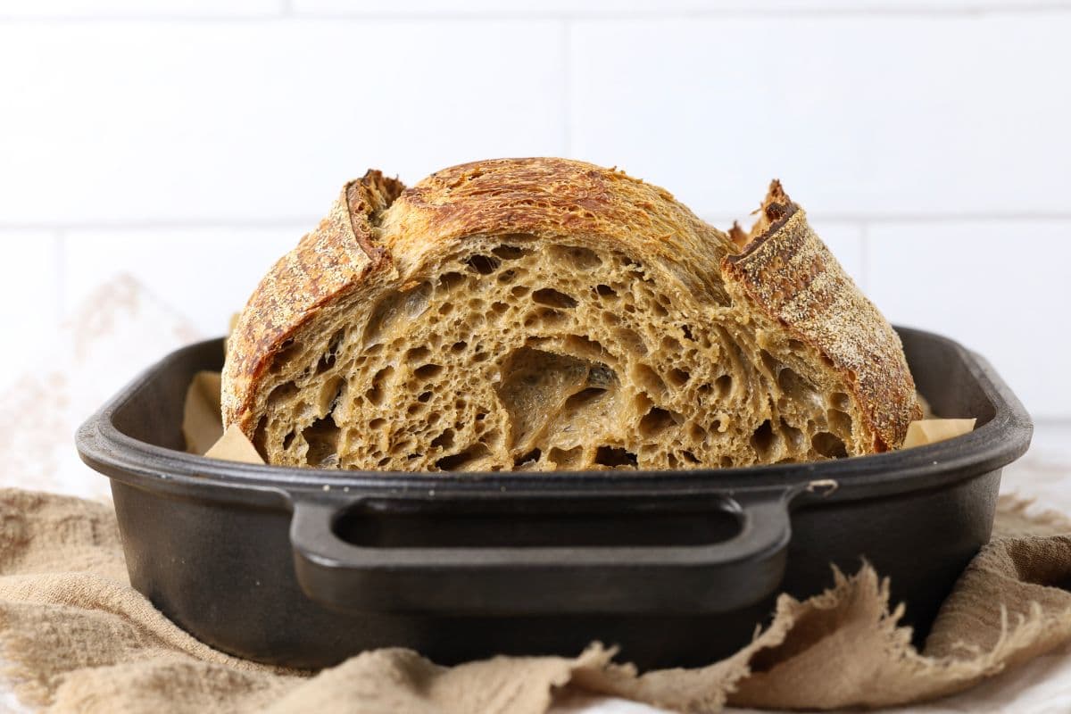 A loaf of cold brew sourdough bread sliced open and inside a Dutch oven.