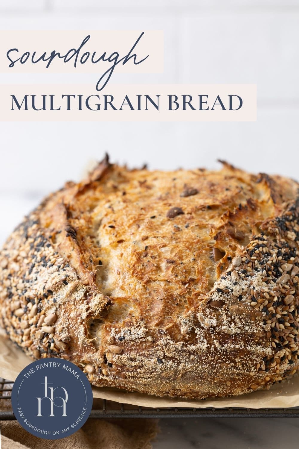 Load of multigrain sourdough bread on a piece of parchment paper with text overlay for a Pinterest Pin.