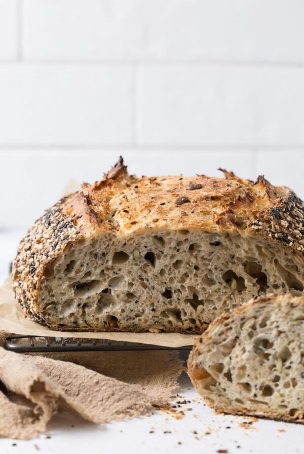 A loaf of multigrain sourdough bread sliced open to show inside texture.