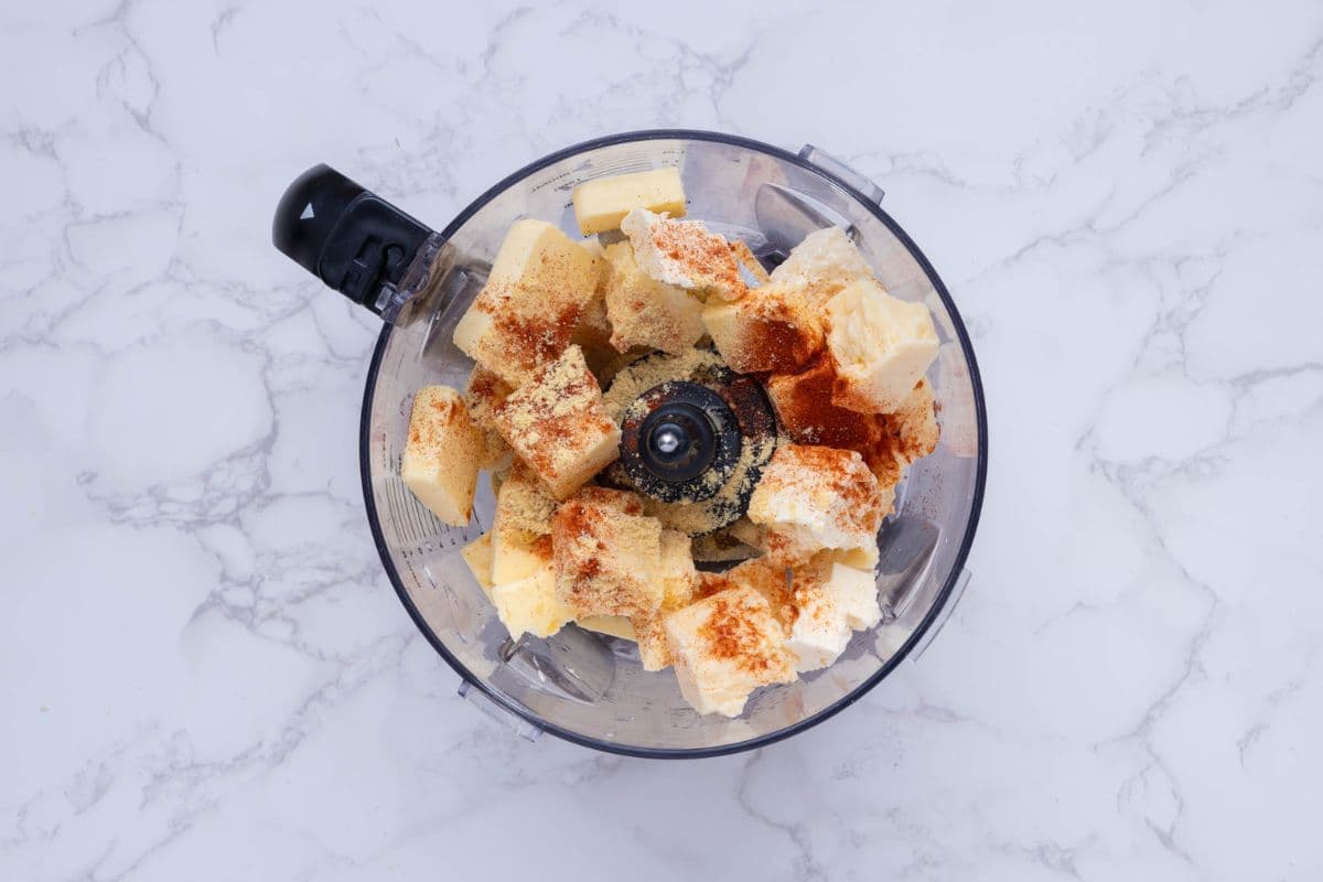 Ingredients for potted cheese being added to food processor.