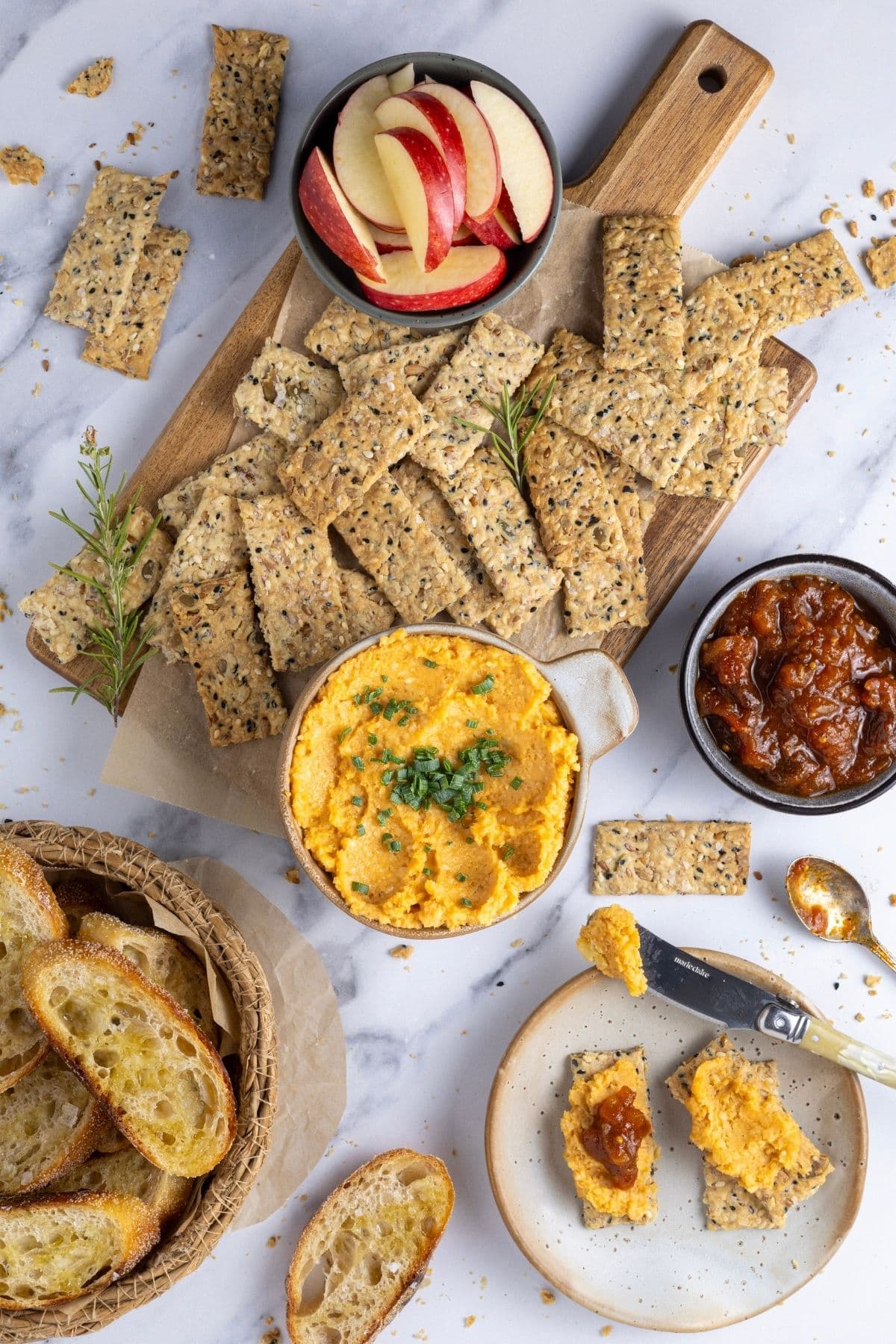 Potted cheese being served with seeded sourdough crackers and sourdough crostini for an appetizer.