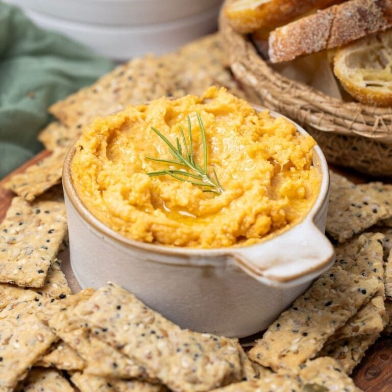 Close up of a bowl of potted cheese with a rosemary sprig on top.