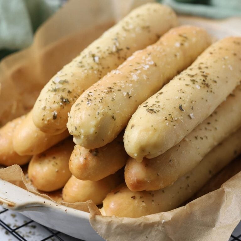 A baking dish with soft sourdough breadsticks stacked for serving.
