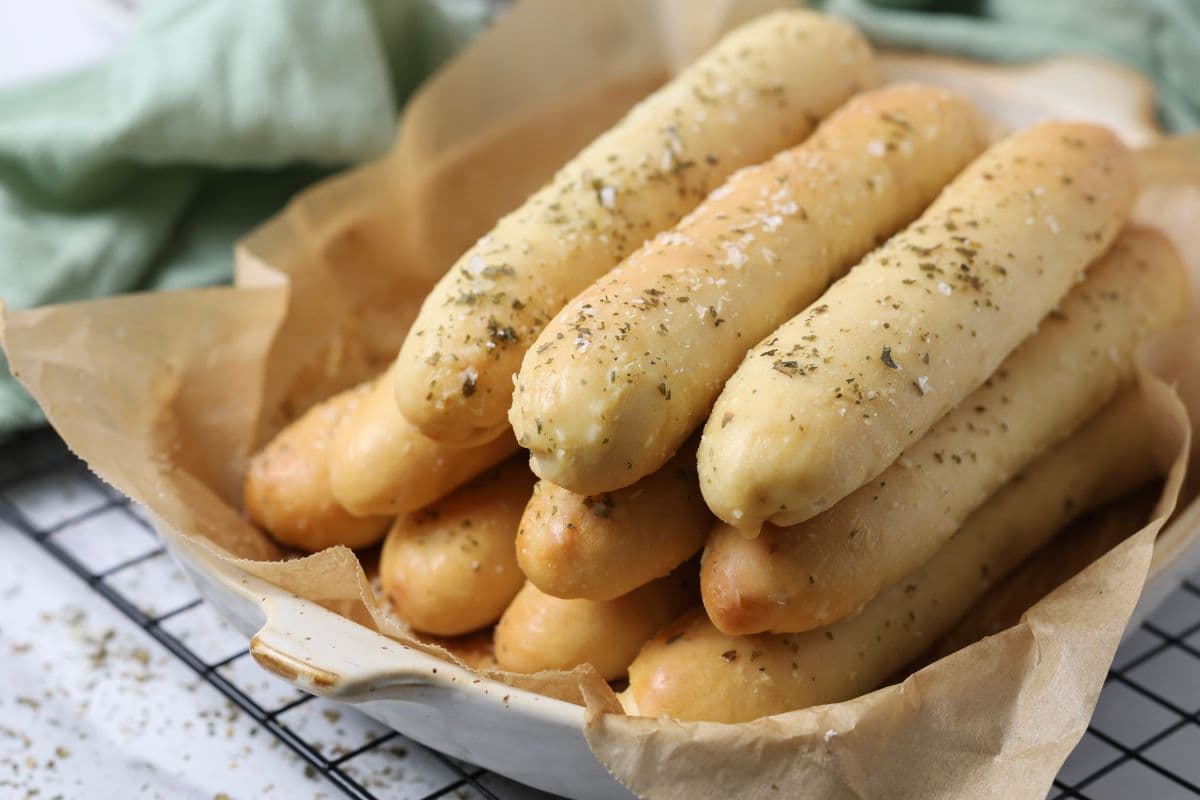 A bowl of soft sourdough breadsticks for serving.