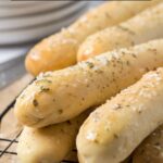 Soft sourdough breadsticks on a cooling rack with text overlay for a Pinterest Pin.