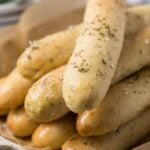 Close up of a soft sourdough breadstick to see fluffy texture and herb topping.