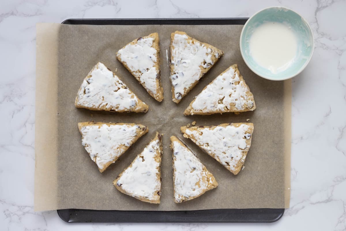 Covering the top of the sourdough chocolate chip scone dough with heavy whipping cream before baking.
