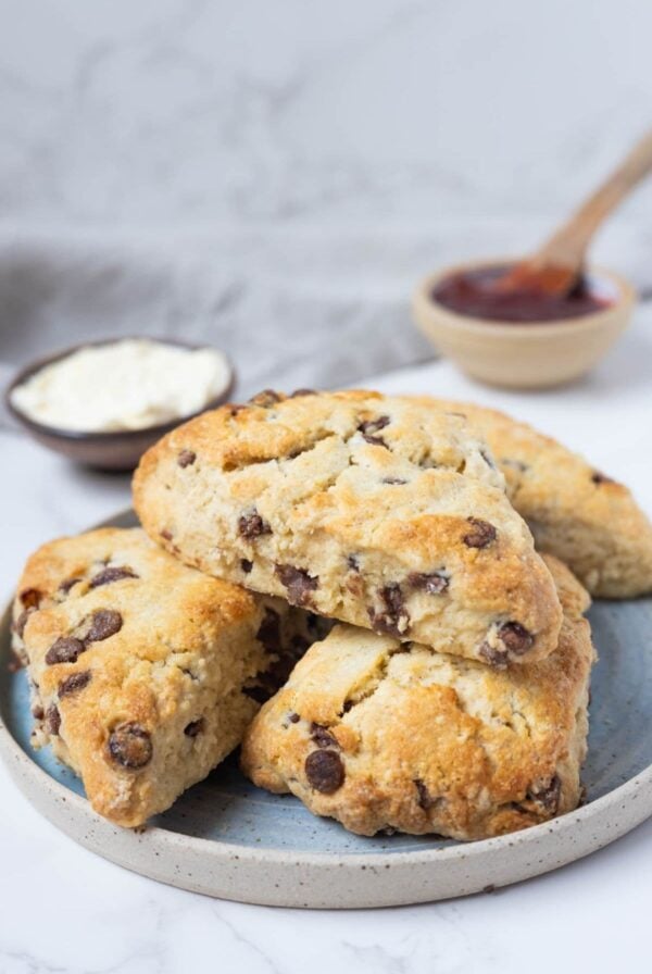 Fresh baked sourdough chocolate chip scones stacked on a small ceramic plate.
