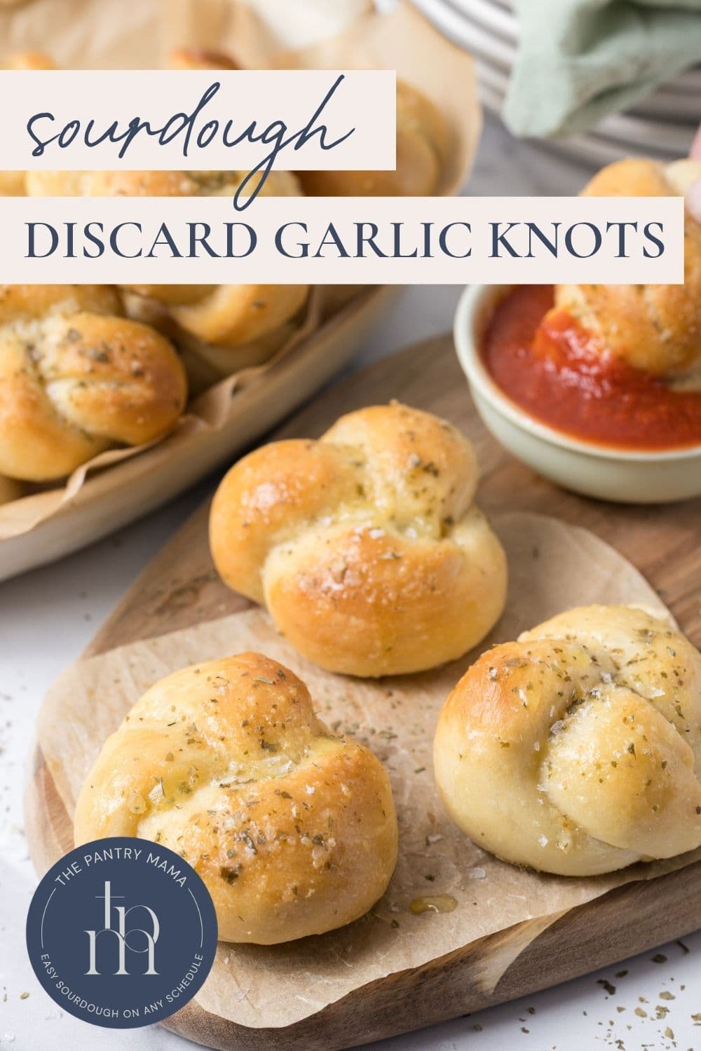 Sourdough discard garlic knots on a wood platter with sauce and text overlay for a Pinterest image.