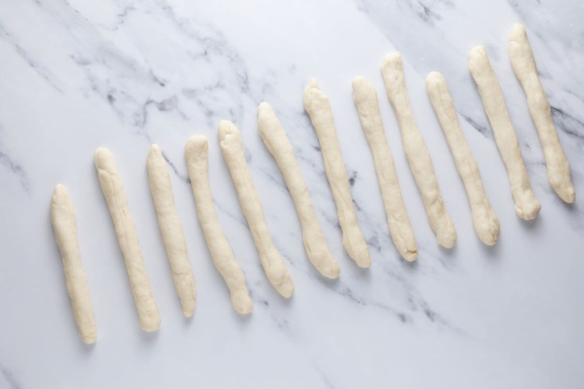 Rolling out the sourdough discard garlic knots dough into ropes for shaping.